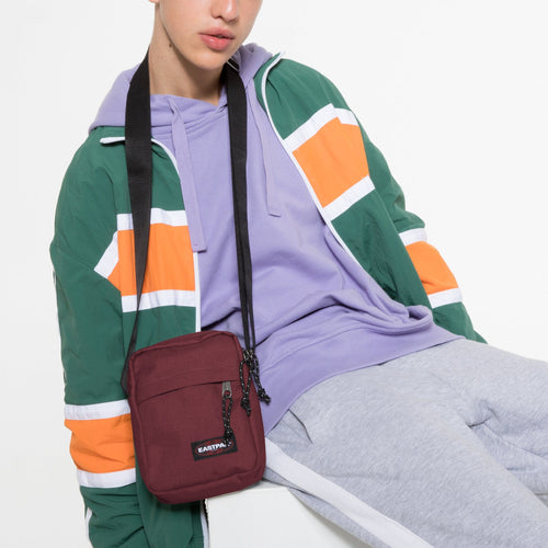 The One Crafty Wine Crossbody Bag Over Neck Of Model Sitting Down